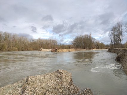 Die Isar hat kurz vor Landau wegen des Hochwassers den künstlichen Kiesdamm gebrochen, der den Hauptarm (links) bislang vom neuen Nebenarm (rechts) getrennt hatte. Den 600 Meter langen Nebenarm graben Bauarbeiter seit Herbst im Rahmen der Isar-Renaturierung aus. 
